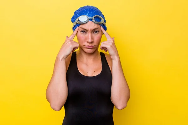 澳大利亚年轻的游泳女子在黄色背景下被隔离 专注于一项任务 食指指向头 — 图库照片