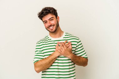 Beyaz arka planda izole edilmiş beyaz tenli genç bir adam, dostane bir ifadeye sahip, avuçlarını göğsüne bastırıyor. Aşk konsepti.