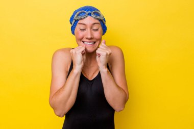 Genç Avustralyalı yüzücü kadın sarı arka planda izole edilmiş mutlu ve başarılı hissediyor. Zafer konsepti.