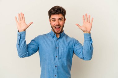Beyaz arka planda izole olmuş genç beyaz bir adam zaferi veya başarıyı kutluyor, şaşırıyor ve şok oluyor..