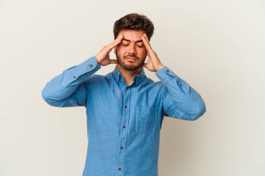 Beyaz arka planda izole olmuş genç beyaz bir adam başı ağrıyor, yüzüne dokunuyor..