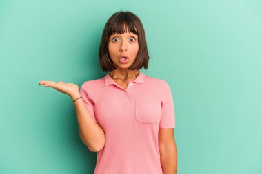 Mavi üzerine izole edilmiş genç melez kadın avuç içinde kopya alanı tutuyor..