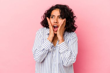 Genç kıvırcık Latin kadın pembe arka planda izole edilmiş korkmuş ve korkmuş..