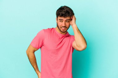 Mavi arka planda izole edilmiş genç beyaz bir adam zaferi, tutkuyu ve coşkuyu kutluyor, mutlu bir ifade..