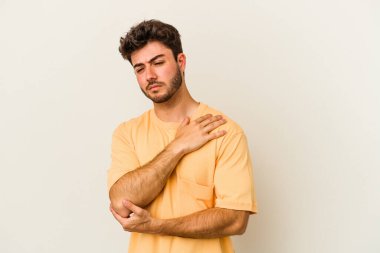 Beyaz arka planda izole edilmiş beyaz tenli genç bir adam kötü bir hareketin ardından acı çekiyor..