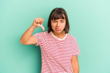 Mavi üzerine izole edilmiş genç bir ırk kadını baş parmağını aşağı gösteriyor ve hoşlanmadığını ifade ediyor..