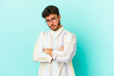 Kafkasyalı genç adam mavi arka planda izole edilmiş şüpheli, belirsiz, seni muayene ediyor..