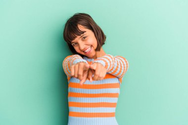 Mavi üzerine izole edilmiş genç melez kadın parmaklarıyla önden öne işaret ediyor..