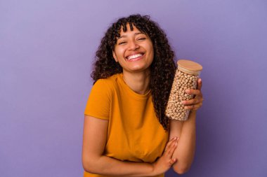 Mor arka planda izole edilmiş nohut şişesini tutan genç Brezilyalı kadın gülüyor ve eğleniyor..