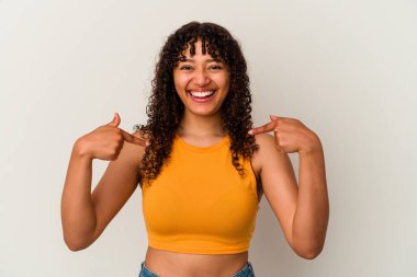 Beyaz arka planda izole edilmiş genç, melez bir kadın parmağını göstererek şaşırdı ve gülümsedi..