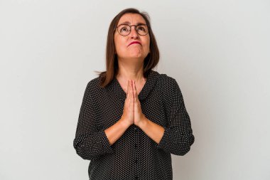 Beyaz arka planda izole edilmiş orta yaşlı beyaz bir kadın el ele dua ederken, kendine güveniyor..