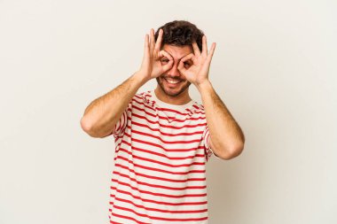 Beyaz arka planda izole edilmiş genç beyaz bir adam gözlerinde sorun olmadığını gösteriyor.