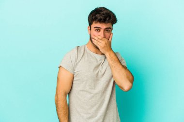 Kafkasyalı genç adam mavi arka planda izole edilmiş korkmuş ve korkmuş..