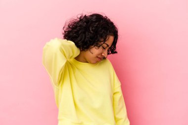 Pembe arka planda izole edilmiş genç kıvırcık Latin kadın stresten dolayı boynu ağrıyor, masaj yapıyor ve elle dokunuyor..