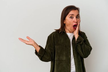 Beyaz arka planda izole edilmiş orta yaşlı beyaz kadın, avuç içi fotokopi alanını elinde tutmaktan etkilenmiş..