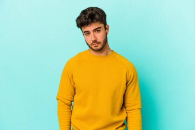 Kafkasyalı genç adam mavi arka planda izole edilmiş üzgün, ciddi yüzlü, mutsuz ve hoşnutsuz..
