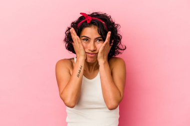 Genç kıvırcık Latin kadın pembe arka planda izole edilmiş sızlanıyor ve ağlıyordu..
