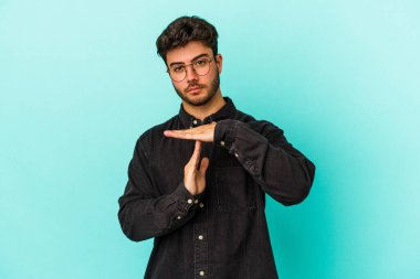 Mavi arka planda izole edilmiş genç beyaz bir adam bir mola hareketi gösteriyor..