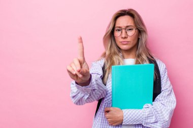 Avustralyalı genç bir öğrenci pembe arka planda izole edilmiş. Parmağıyla bir numarayı gösteriyor..