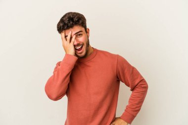 Beyaz arka planda izole edilmiş genç beyaz bir adam yüzünün yarısını palmiye ile örterek eğleniyor..