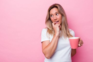 Pembe arka planda izole edilmiş pembe kupa tutan genç Avustralyalı kadın bir şeyin fotokopi odasına baktığını düşünerek rahatladı..