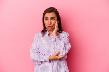 Pembe arka planda izole edilmiş orta yaşlı beyaz kadın yanakları patlamış, yorgun bir ifadesi var. Yüz ifadesi kavramı.