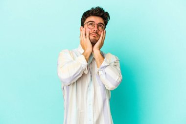 Kafkasyalı genç adam mavi arka planda izole edilmiş sızlanıyor ve ağlıyordu..