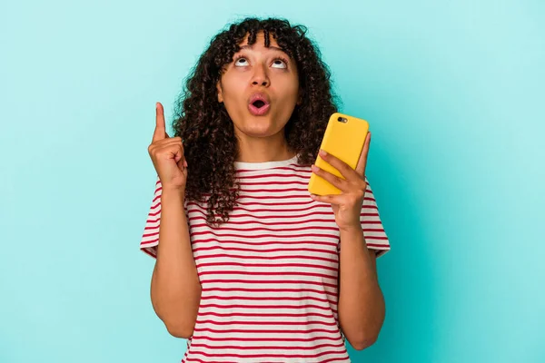 Молодая Женщина Смешанной Расы Держит Мобильный Телефон Изолирован Синем Фоне — стоковое фото