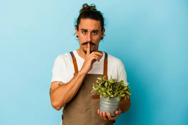 Jovem Jardineiro Caucasiano Segurando Uma Planta Isolada Fundo Azul Mantendo — Fotografia de Stock