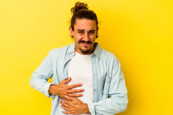 黄色の背景に肝臓の痛み 胃の痛みを持って隔離された長い髪を持つ若い白人男性 — ストック写真