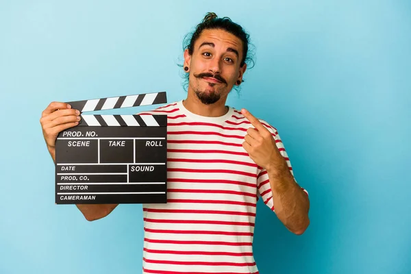 Mladý Běloch Dlouhými Vlasy Drží Clapperboard Izolované Modrém Pozadí Ukazuje — Stock fotografie