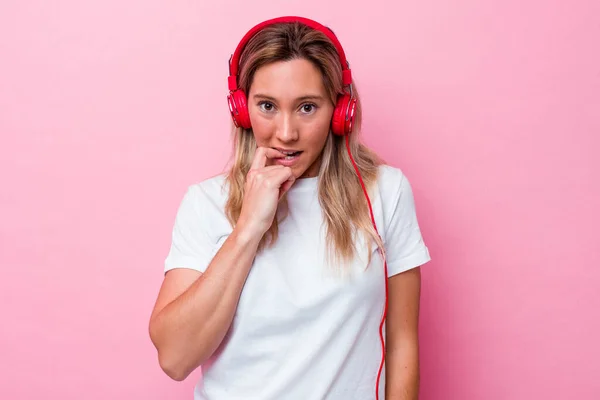 Νεαρή Αυστραλή Γυναίκα Ακούει Μουσική Απομονωμένη Ροζ Φόντο Δαγκώνοντας Νύχια — Φωτογραφία Αρχείου