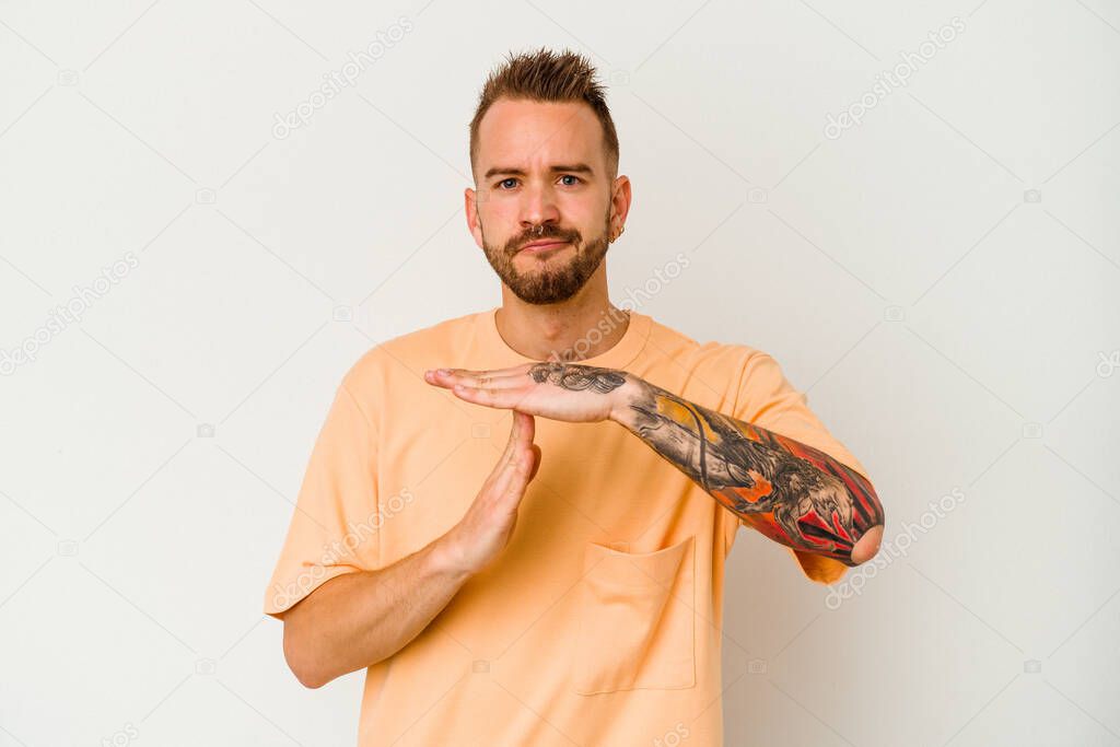 Young tattooed caucasian man isolated on white background showing a timeout gesture.