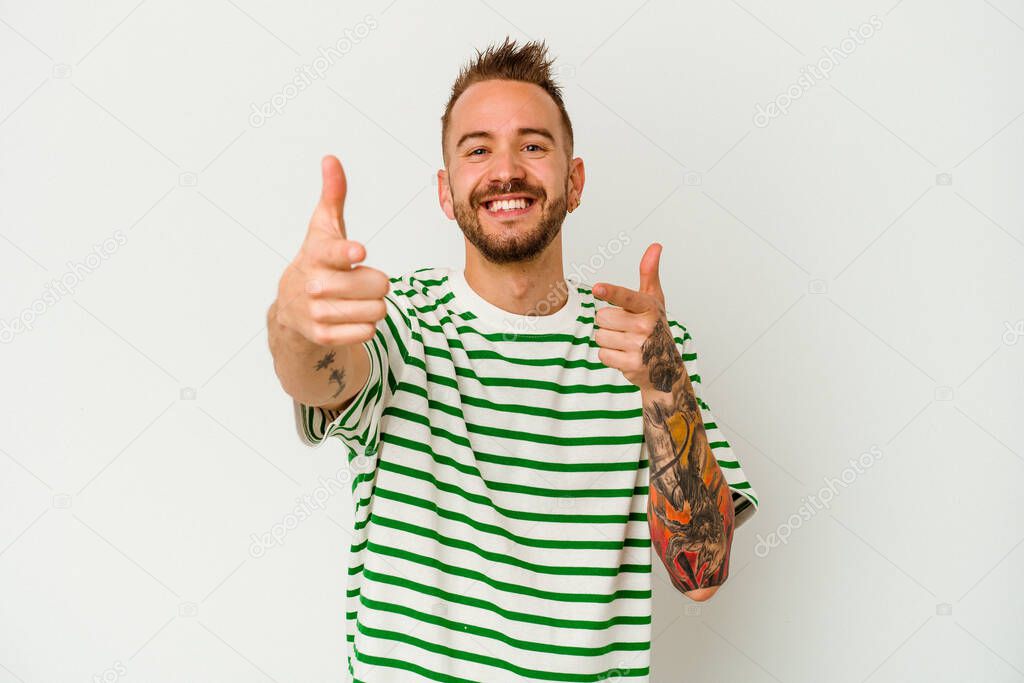 Young tattooed caucasian man isolated on white background cheerful smiles pointing to front.