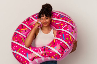 Beyaz arka planda izole edilmiş şişme bir donut tutan genç bir ırk kadını parmağıyla tapınağı işaret ediyor, düşünüyor ve bir göreve odaklanıyor..