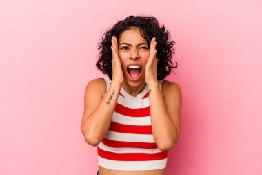 Genç kıvırcık Latin kadın pembe arka planda izole edilmiş kulakları kulaklarıyla kapatıyor çok fazla ses duymamaya çalışıyor..