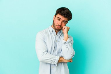 Mavi arka planda izole edilmiş genç beyaz adam tekrarlanan bir görevden yoruldu..