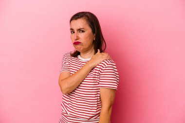 Pembe arka planda izole edilmiş orta yaşlı beyaz kadın omuz ağrısı çekiyor..