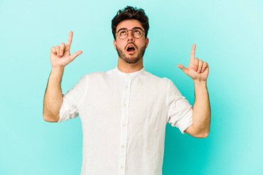 Mavi arka planda izole edilmiş beyaz bir adam ağzı açık bir şekilde üst tarafı işaret ediyor..