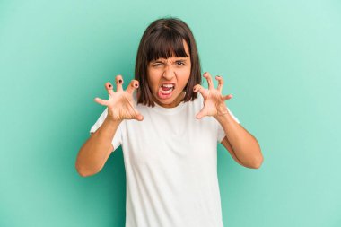 Mavi üzerine izole edilmiş genç melez kadın pençelerini bir kediyi taklit ederken gösteriyor, agresif bir hareket..