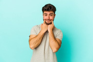 Kafkasyalı genç adam mavi arka planda izole edilmiş iki seçenek arasında şüphe duyuyor.