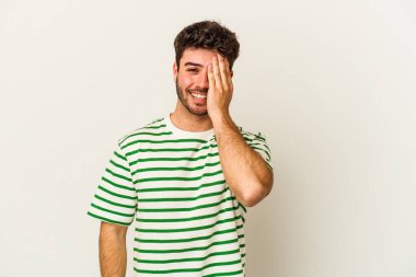 Beyaz arka planda izole edilmiş genç beyaz bir adam yüzünün yarısını palmiye ile örterek eğleniyor..