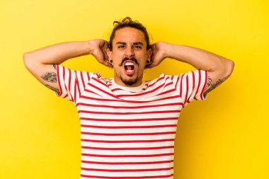 Sarı arka planda izole edilmiş uzun saçlı beyaz bir adam öfkeyle bağırıyor..