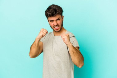 Mavi arka planda izole edilmiş genç beyaz adam gergin elleriyle çığlık atıyor..