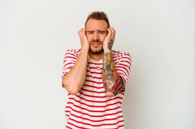 Beyaz arka planda izole edilmiş beyaz dövmeli genç bir adam ağlıyor, bir şeyden memnun değil, acı ve kafa karışıklığı konsepti..