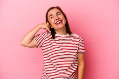 Pembe arka planda izole edilmiş orta yaşlı beyaz kadın parmakları olan bir cep telefonu hareketi gösteriyor..