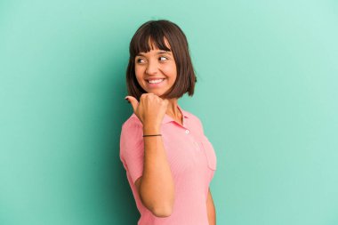 Genç melez kadın mavi noktalarda izole edilmiş, başparmak uzakta, gülüyor ve kaygısız..