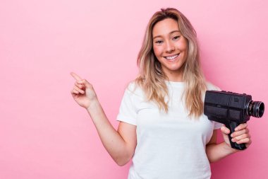 Avustralyalı genç bir kadın, izole edilmiş, gülümseyen ve işaret eden eski bir video kamerayla çekim yapıyor..