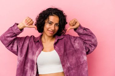 Pembe arka planda soyutlanmış genç kıvırcık Latin kadın gururlu ve kendinden emin hissediyor, örnek olarak.