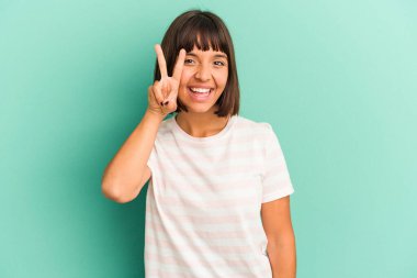 Mavi üzerine izole edilmiş genç melez kadın iki numarayı parmaklarıyla gösteriyor..